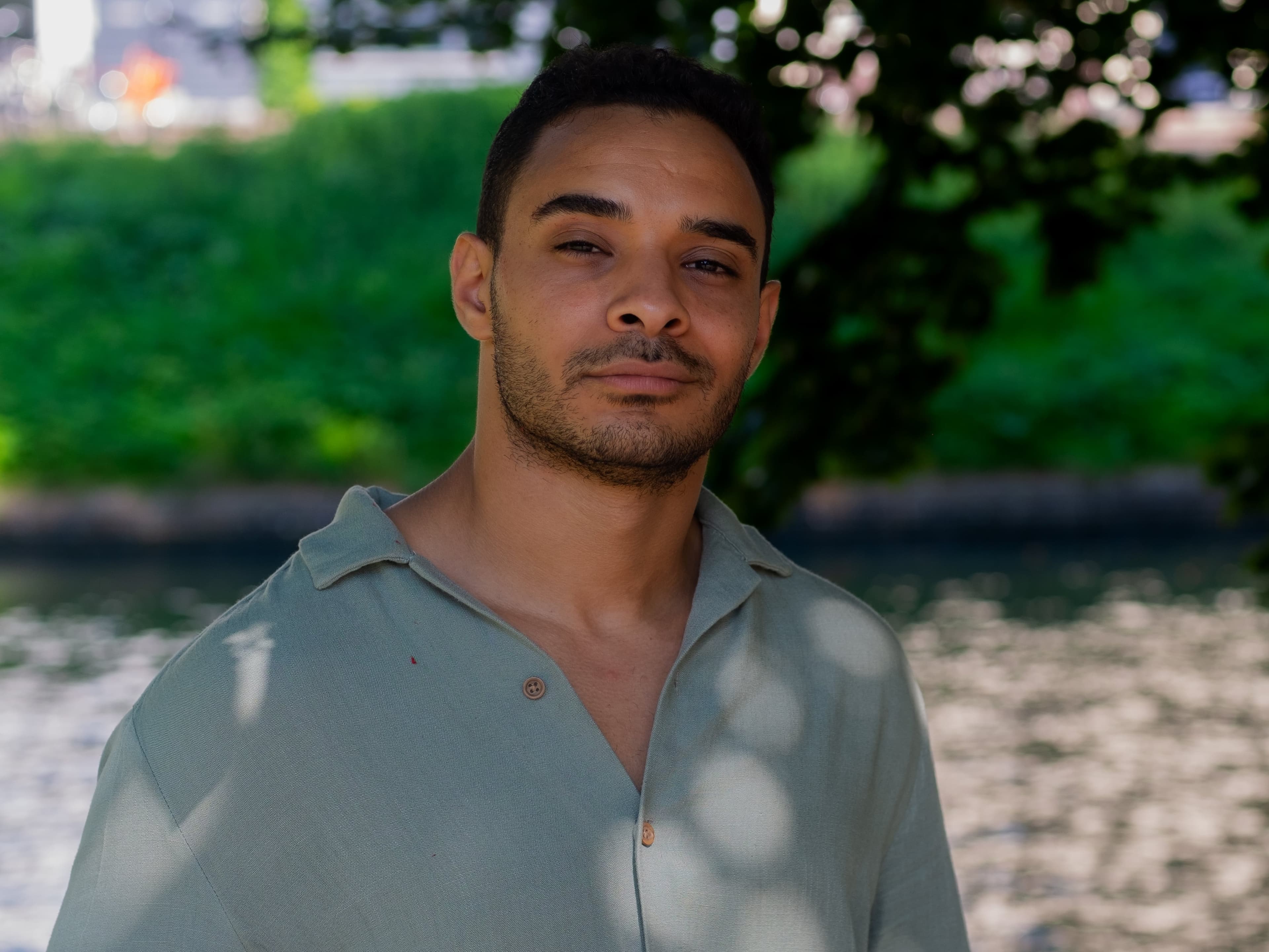 A portrait of Hithem standing by the Canal, with a serene river flowing in the background.